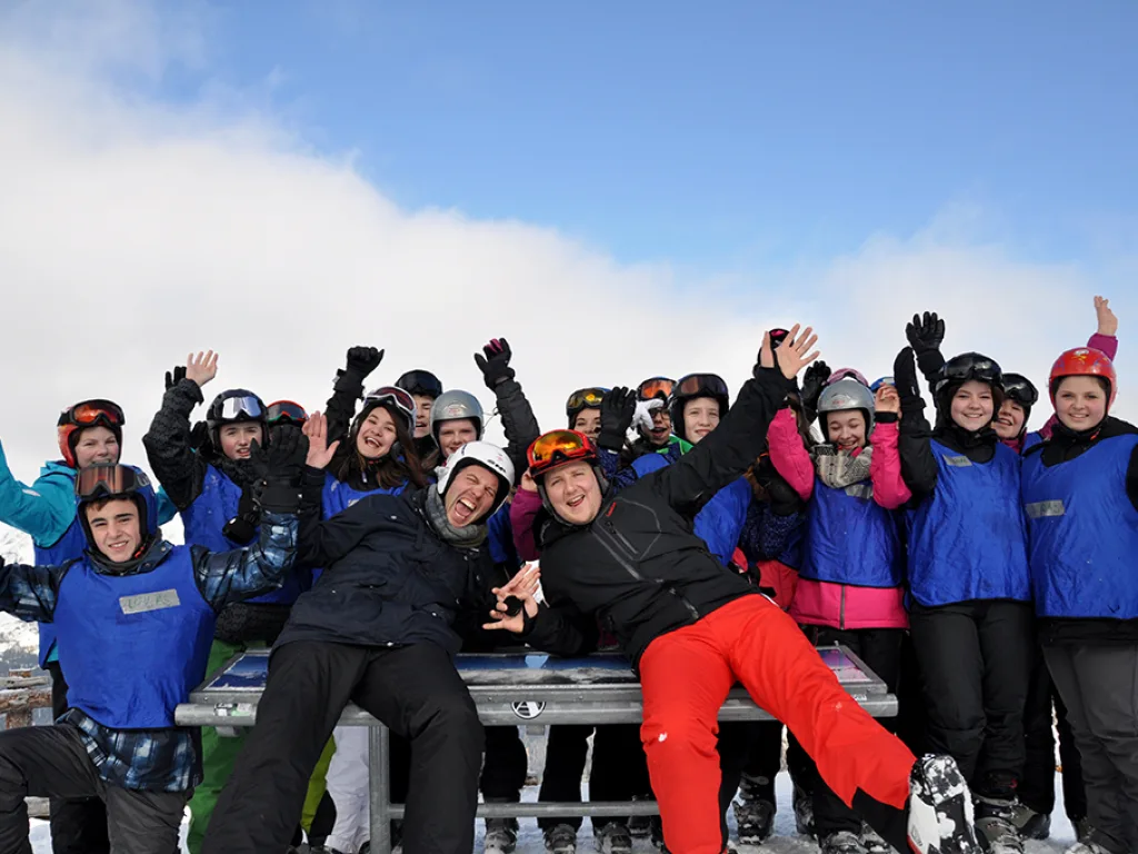 Ausgelassene Gruppe auf einer Bank vor blauem Himmel.